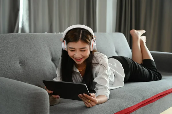 Piękna Młoda Azjatka Używa Smartfona Słucha Muzyki Słuchawkach Leżąc Kanapie — Zdjęcie stockowe