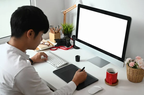 彼のワークスペース上のグラフィックタブレット上で働く若いアジアのグラフィックデザイナー — ストック写真