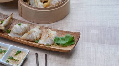 Japon gyoza 'sı, dikdörtgen ahşap tabakta hamur tatlısı ve ahşap masada çubuklar..
