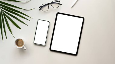 Boş ekran tabletli, akıllı telefonlu, kahveli, yeşil yapraklı ofis masasının düz bir fotoğrafı..