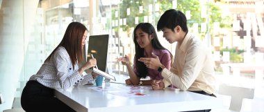 Bir grup insan tasarımcı toplantı odasında cep telefonu ve ilgili web sitelerinin kablo grafiksel uygulamalarını tasarlıyor..