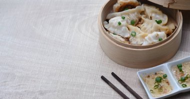 Bambu buharlı hamur köfteleri, erik sosu ve ahşap masa üzerinde fotokopi alanı olan çubuklar..