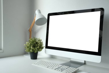 Boş beyaz masaüstü bilgisayarı, lambası ve bitkisi olan çalışma alanı. Grafik görüntüleme kurgusu için boş ekran.