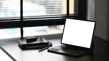 Boş ekran tablet bilgisayar, defter, kalem ve gözlükler siyah tahta masada. Ürün görüntüleme kurgusu için boş ekran.