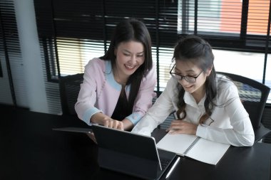 İş kadınları, meslektaşlarıyla iş yerinde ortak bir proje üzerinde işbirliği yaparken parmaklarını bilgisayar tabletine koyuyorlar..