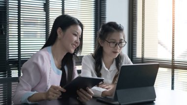 İş kadını, modern bir iş salonundaki meslektaşlarına fikirlerini göstermek için bilgisayar tableti kullanıyor..