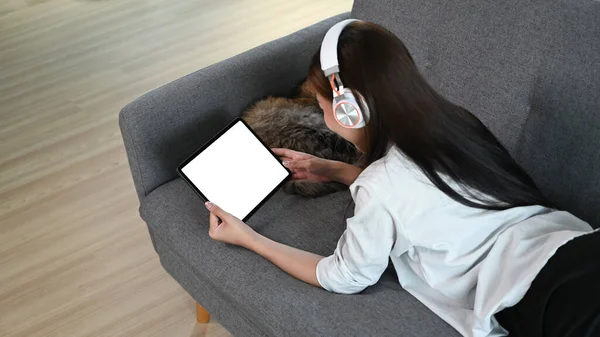 소파에 헤드폰으로 음악을 태블릿을 사용하고 있습니다 — 스톡 사진