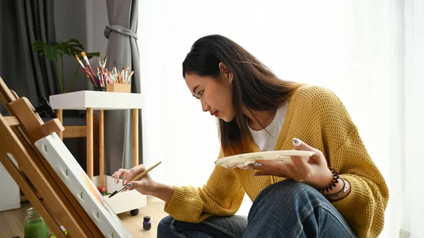 Een Geconcentreerde Jonge Vrouwelijke Kunstenaar Zittend Vloer Met Schilderaccessoires — Stockfoto