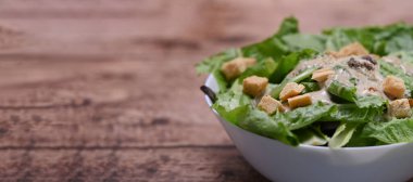 Tahta masada bir kase sezar salatası. Metnin için boşluk kopyala.