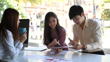 Asyalı ux geliştirici ve ui tasarımcısı modern ofis masasında mobil uygulama arayüzü kablo tasarımı hakkında beyin fırtınası yapıyorlar..
