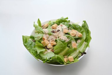 Beyaz arka planda marul, pastırma ve kızarmış ekmekle sezar salatası..