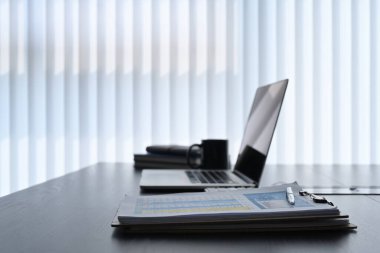 Karanlık ofis masasında bilgisayar, belge ve kahve fincanı olan modern işyeri.