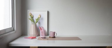 Kahve fincanı, akıllı telefon, çiçekler ve beyaz masadaki kopyalama alanı olan kadınsı işyeri.