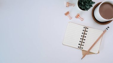 Boş defterli beyaz ofis masasının üst görüntüsü. kalem, kahve fincanı ve kopyalama alanı.