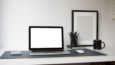 Boş ekranlı bilgisayar bilgisayarı, akıllı telefon, kalem tutacağı ve ofis masasında boş çerçeve.
