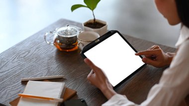 Kafede oturup dijital tablet kullanan sıradan bir kadının görüntüsü..