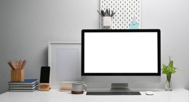 Workspace computer mockup and office supplies with peg board on wooden table.	