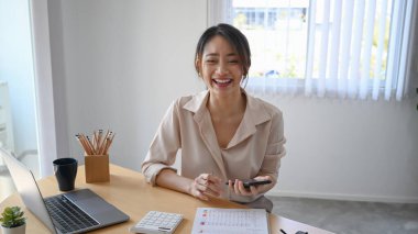 Neşeli kadın muhasebeci hesap makinesi kullanıyor ve gülüyor.