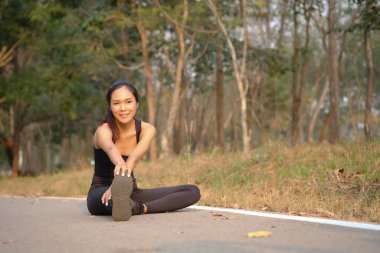 Genç bayan koşucu dışarıda egzersiz yapmadan önce bacaklarını esnetiyor..