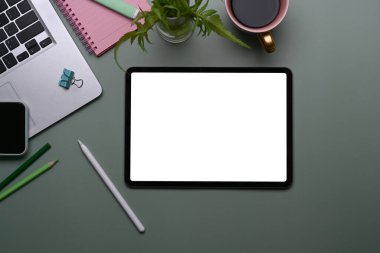 Dijital tabletin üst görüntüsü, dizüstü bilgisayar, kahve fincanı ve koyu yeşil arkaplan üzerine not defteri.