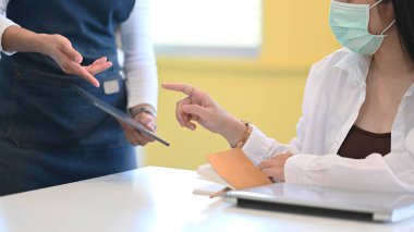 Garson, kahve dükkanında veya restoranda menü seçmek için müşteriye tablet kullanıyor.