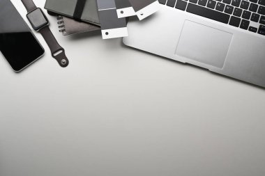 Dizüstü bilgisayarı, akıllı saati, akıllı telefonu ve beyaz masadaki boşluğu kopyalayan grafik tasarımcı işyeri görünümünün üstünde.