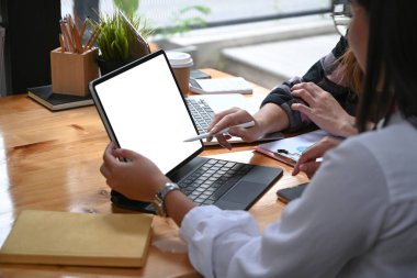 Bilgisayar tabletiyle çalışan ve yaratıcı ofiste fikirleri tartışan iki tasarımcının görüntüsü..