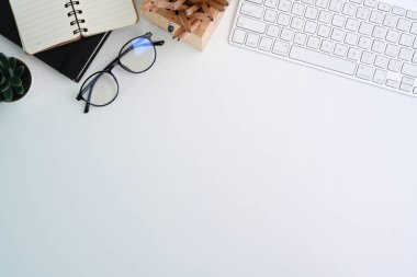 Klavyeli, gözlüklü ve defterli beyaz ofis masasının üst görüntüsü. Reklam metni için alanı kopyala.