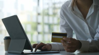 Kredi kartı ve online alışveriş yapan genç bir bayanın eksiltilmiş görüntüsü veya bilgisayar tableti ile çevrimiçi ödeme.