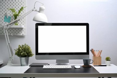 Bilgisayarı, tesisi ve ofis tedarikçilerini beyaz masaya yerleştiren modern işyeri..