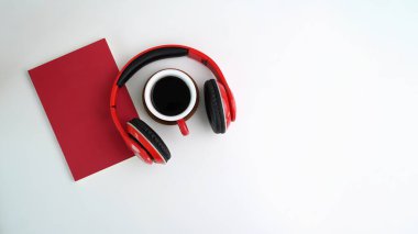 Kulaklık, not defteri ve beyaz arka planda kahve fincanı. Kopyalama alanı olan üst görünüm.