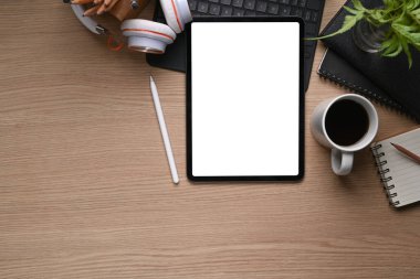 Dijital tablet, stilus kalem, kahve fincanı ve telefon ahşap masaya..