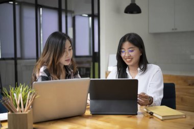 Modern ofiste yeni başlatılan projeyle çalışan iki genç tasarımcı.