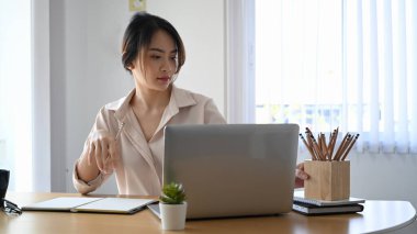 Yaratıcı ofiste dizüstü bilgisayarla çalışan kendine güvenen genç kadın tasarımcı..