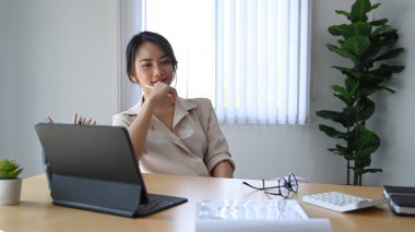 Çağdaş bir ofiste masasında güvenle oturan genç bir kadın..