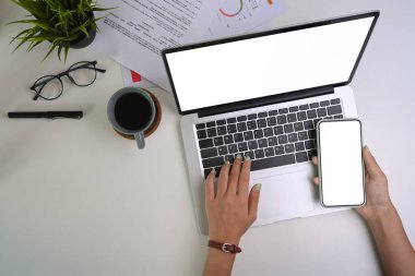 İş kadını elinin cep telefonu tutması ve dizüstü bilgisayarda yazması..