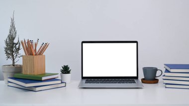 Bilgisayarlı ofis masası, kahve fincanı, ev bitkisi ve kutular beyaz masada..
