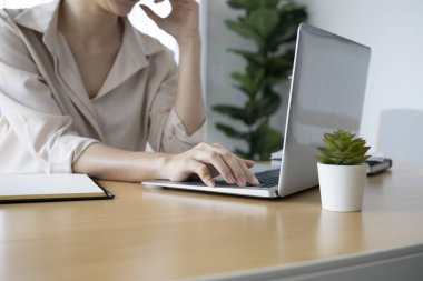 Genç kadın muhasebeci, modern işyerindeki dizüstü bilgisayarlar üzerinde yoğunlaşır..