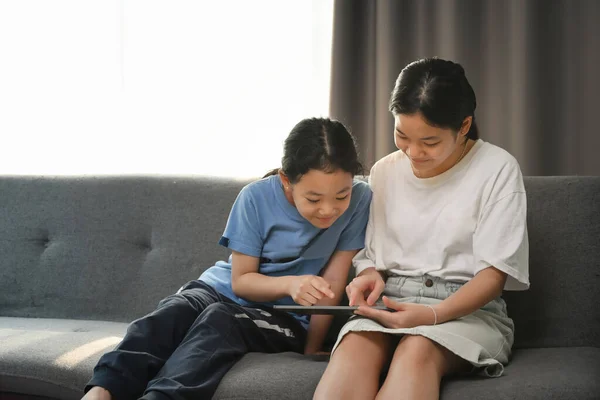 Asian Girl Her Sister Using Digital Tablet Together While Siting — Zdjęcie stockowe
