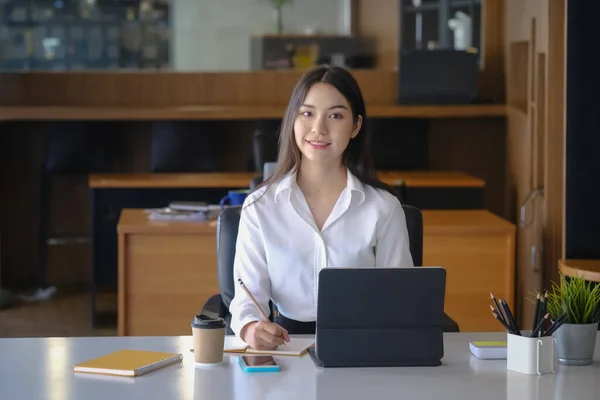 若いアジアの女性のオフィスワーカーは オフィスの机でコンピュータタブレットと座って カメラに笑顔 — ストック写真