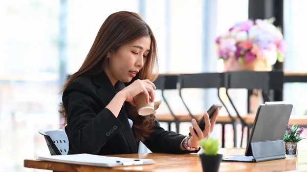 Νεαρή Γυναίκα Επιχειρηματίας Χρησιμοποιώντας Έξυπνο Τηλέφωνο Πίνοντας Ζεστό Ρόφημα Πρωί — Φωτογραφία Αρχείου