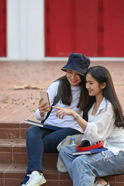 Dwóch Studentów Siedzi Kampusie Szuka Smartfona Sprawdzić Dobre Wieści — Zdjęcie stockowe