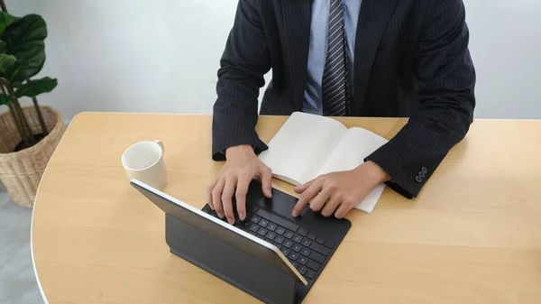 木製のオフィスデスクでコンピュータタブレット上で働くビジネスマンの作物のショット — ストック写真