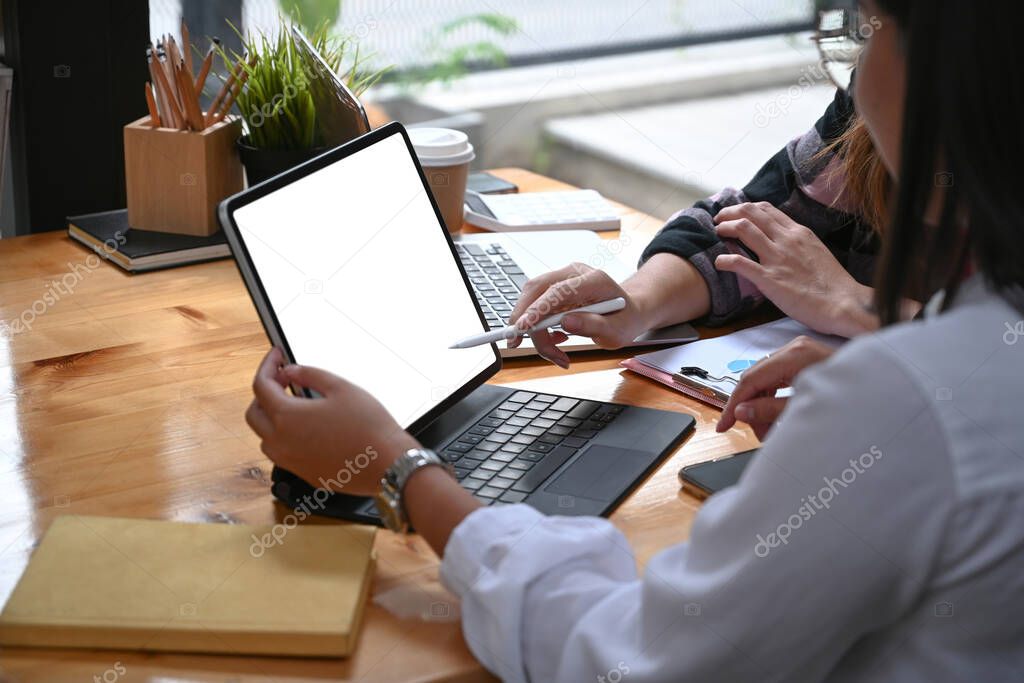 Cropped shot of two designer working with computer tablet and discussing ideas at creative office.