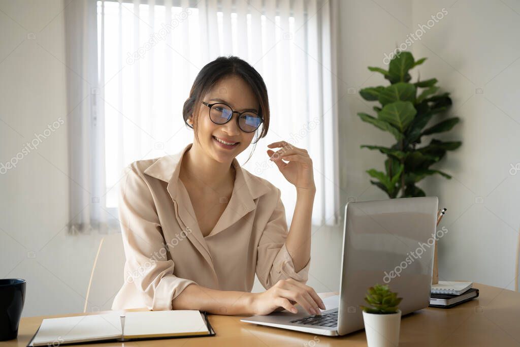 Happy young woman office worker working with computer laptop in office and smiling to camera.