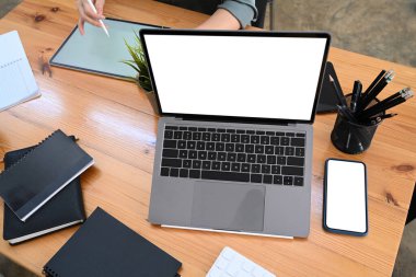 Boş ekranlı dizüstü bilgisayar ve ahşap ofis masasında akıllı telefon..