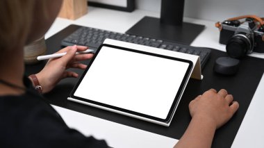 Yaratıcı ofiste dijital tabletle çalışan kadın fotoğrafçının yakın görüntüsü.