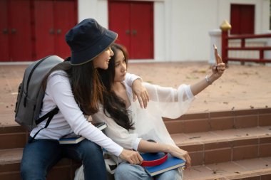 Neşeli üniversite öğrencileri derslerden sonra eğleniyor ve bir üniversite kampüsünde selfie çekiyor..