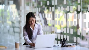 Modern ofiste bilgisayarla çalışan sakin bir iş kadını..