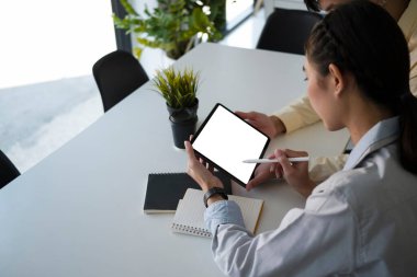 Dijital tablet üzerinde çalışan ve mali projeyi tartışan genç iş adamları.